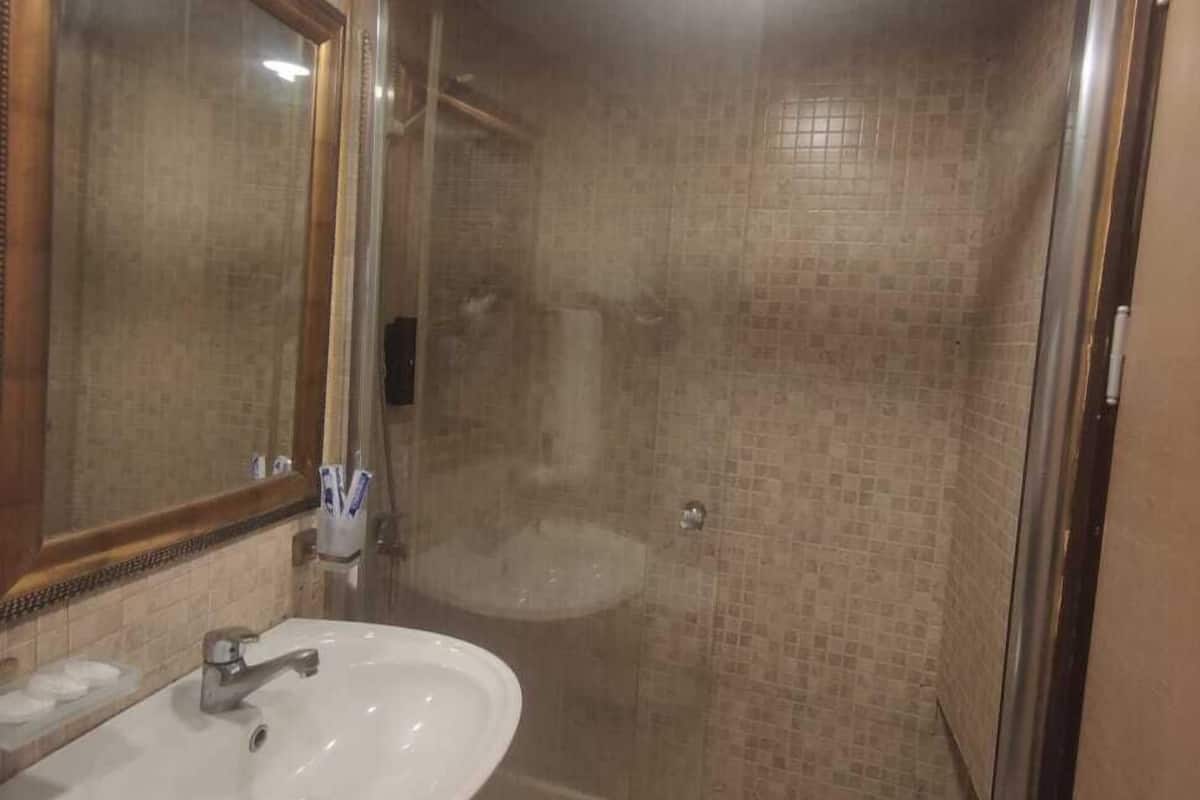 A bathroom with a glass-enclosed shower, a sink, and a mirror.