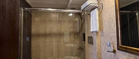 A modern bathroom with a glass-enclosed shower, a white sink, and a large mirror.