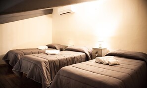 A room with two beds, each with a pillow and a rolled towel. There is a nightstand with a lamp and a small drawer. - Podere Giulio (Tarquinia)