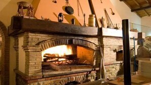 Un horno de leña tradicional de piedra, con base de ladrillo y techo de madera.