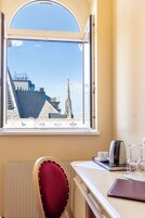 A room with a large window, a radiator, a red chair, a table with a kettle, glasses, and a notebook.