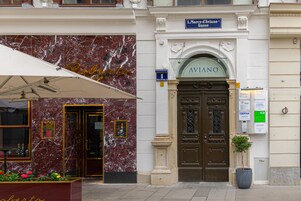 A hotel entrance with a marble facade, a large entrance door, and a sign reading "AVIANO".