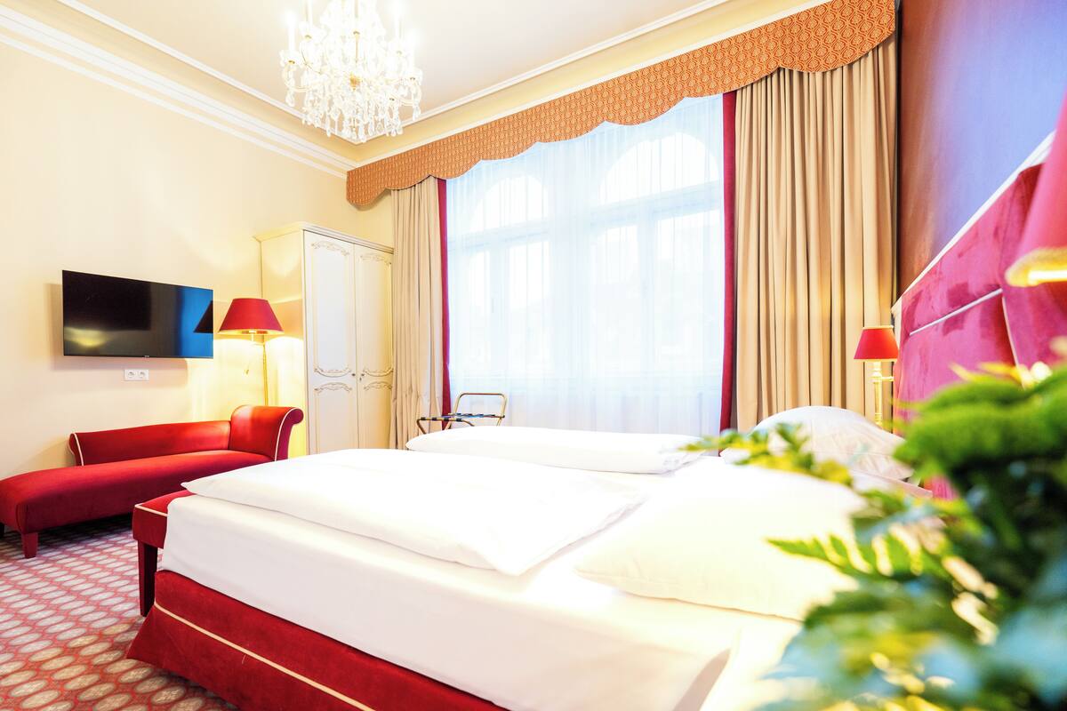 A hotel room with a large bed, a TV, a desk, and a chair.