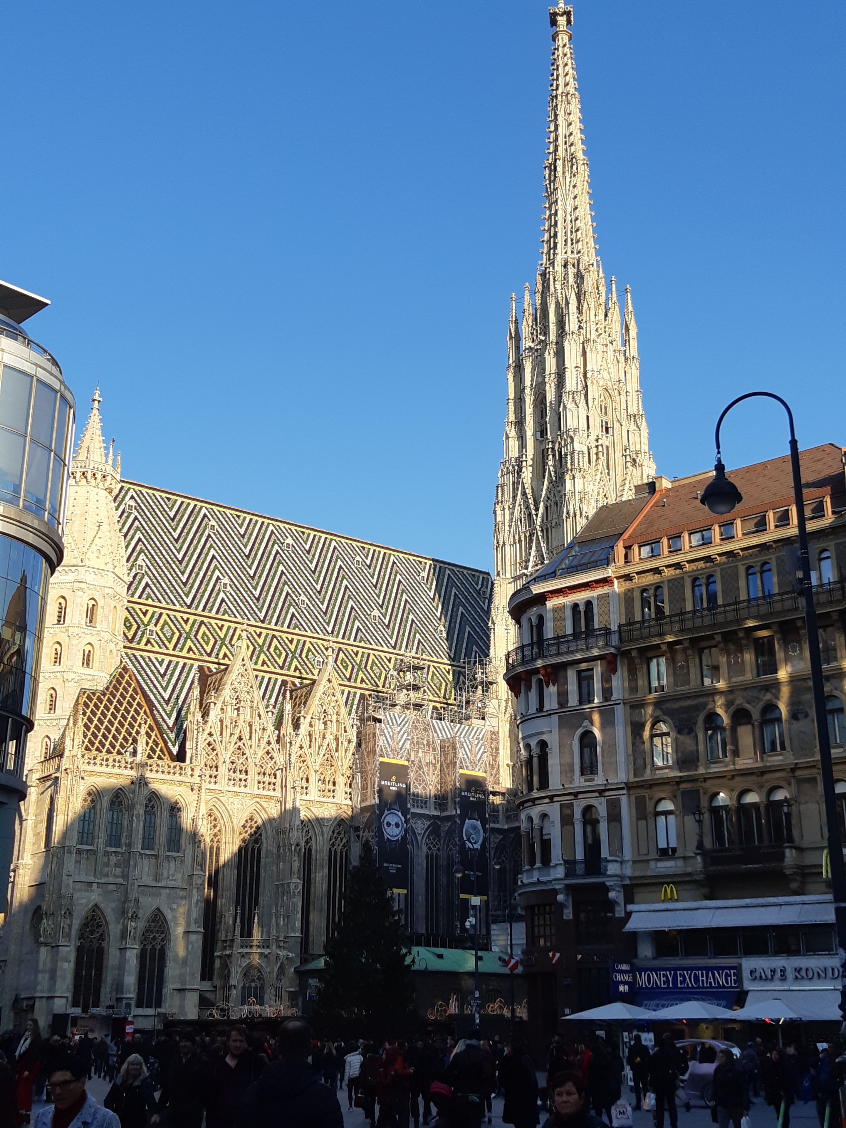 Un edificio storico con elaborata architettura gotica, caratterizzato da una guglia slanciata e una facciata riccamente decorata.