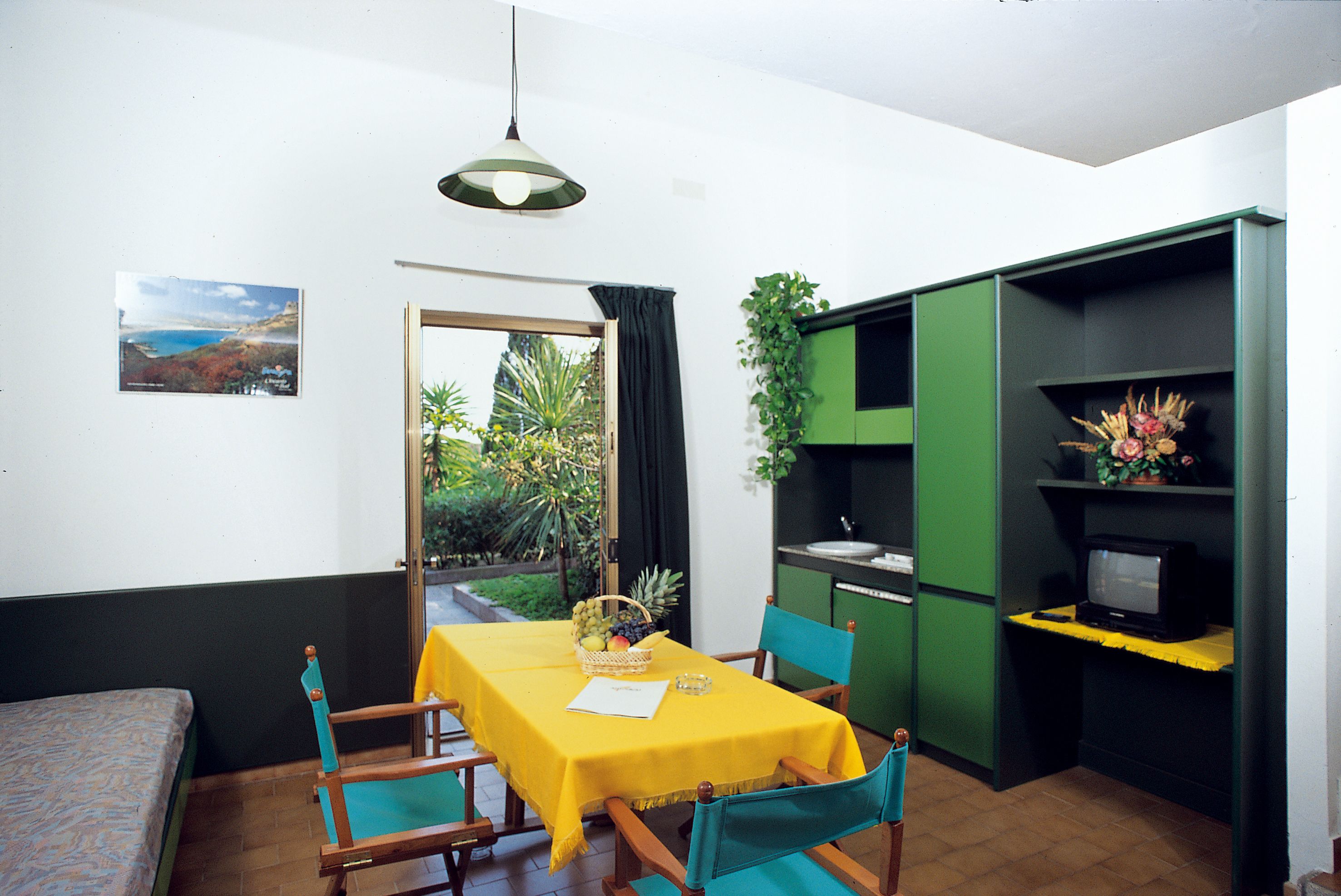 Un espacio habitable compacto con una mesa de comedor, sillas, una pequeña cocina y un televisor.
