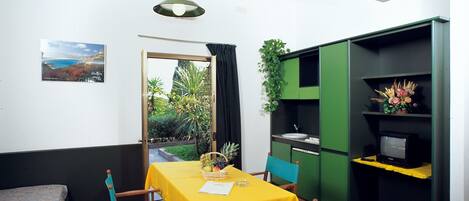 Ett kompakt bostadsutrymme med ett matbord, stolar, ett litet köksområde och en tv.