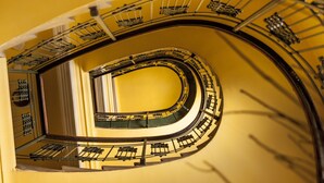 Una escalera en espiral con pared amarilla y barandales de metal.