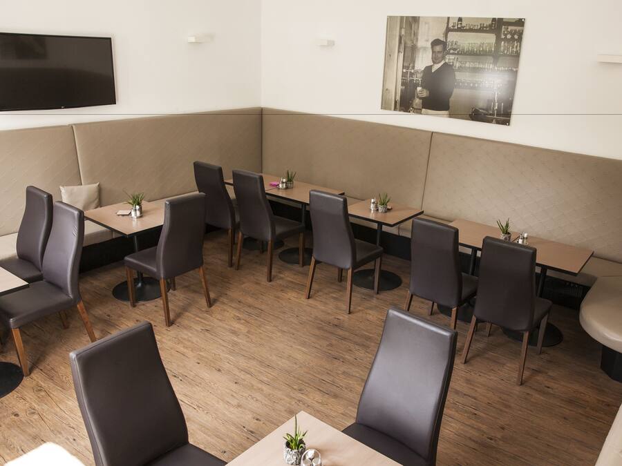Un restaurante moderno con cabinas y mesas, un televisor de pantalla plana en la pared y un cuadro enmarcado sobre la zona de estar.