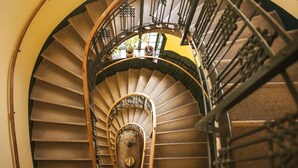 Una escalera de caracol con barandilla metálica y un reloj en el centro.