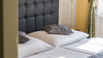 A bed with a tufted headboard, two pillows, and a bedside lamp.