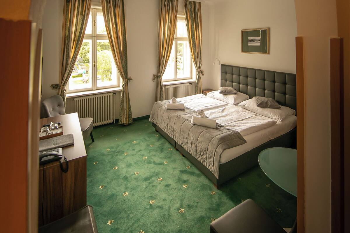 Ein Hotelzimmer mit einem Bett, einem Schreibtisch, einem Sessel und einem kleinen Tisch.