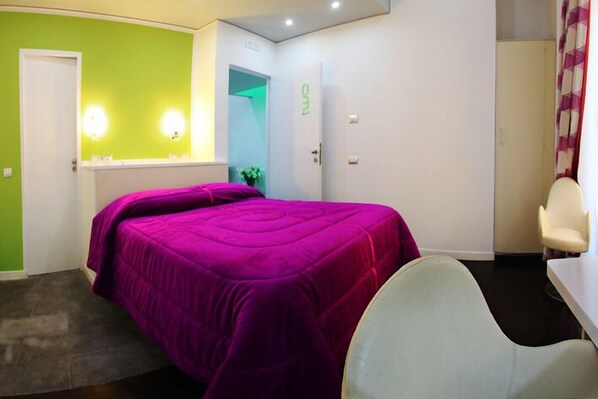 Une pièce comprenant un lit, une chaise, un bureau et une porte menant à la salle de bain.