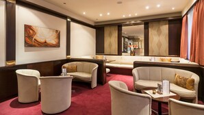 A modern hotel lobby with a seating area featuring sofas and armchairs, a large mirror, and artwork on the walls. - Club Hotel Cortina (Vienna)