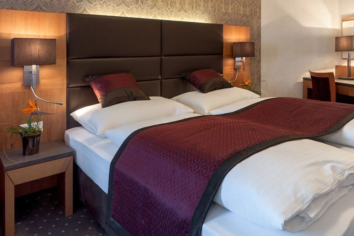 A hotel room with a large bed, two bedside tables, a desk, and a mirror.