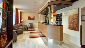 A modern lobby with a reception desk, seating area, and artwork. - Club Hotel Cortina (Vienna)
