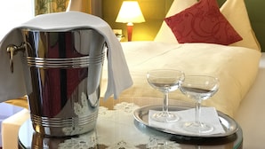 A hotel room with a bed, a bedside table with a tray holding two glasses, and a metallic container. - Hotel Austria (Vienna)