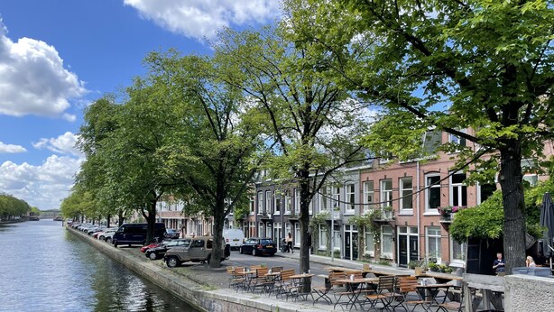 A canal-side walkway with benches and tables, lined with trees and residential buildings. - Bed and Breakfast Amsterdam (Amsterdam)