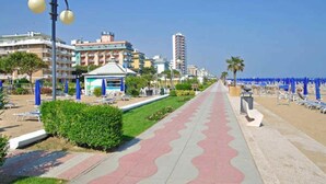 A coastal promenade with a paved walkway, beach umbrellas, and buildings in the background. - Relais Villa Selvatico (Roncade)