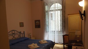 A bedroom with a bed, a chair, a desk, and a window with curtains. - Relais del Duomo (Florence)