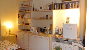 A cozy room with a kitchenette, a dining area with a table and chairs, and shelves with books and kitchen items. - Relais del Duomo (Florence)