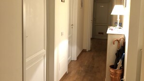 A hallway with wooden flooring, white doors, and a lamp on a table. - Relais del Duomo (Florence)