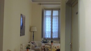 A dining area with a table and chairs, a lamp, and a window with curtains. - Relais del Duomo (Florence)
