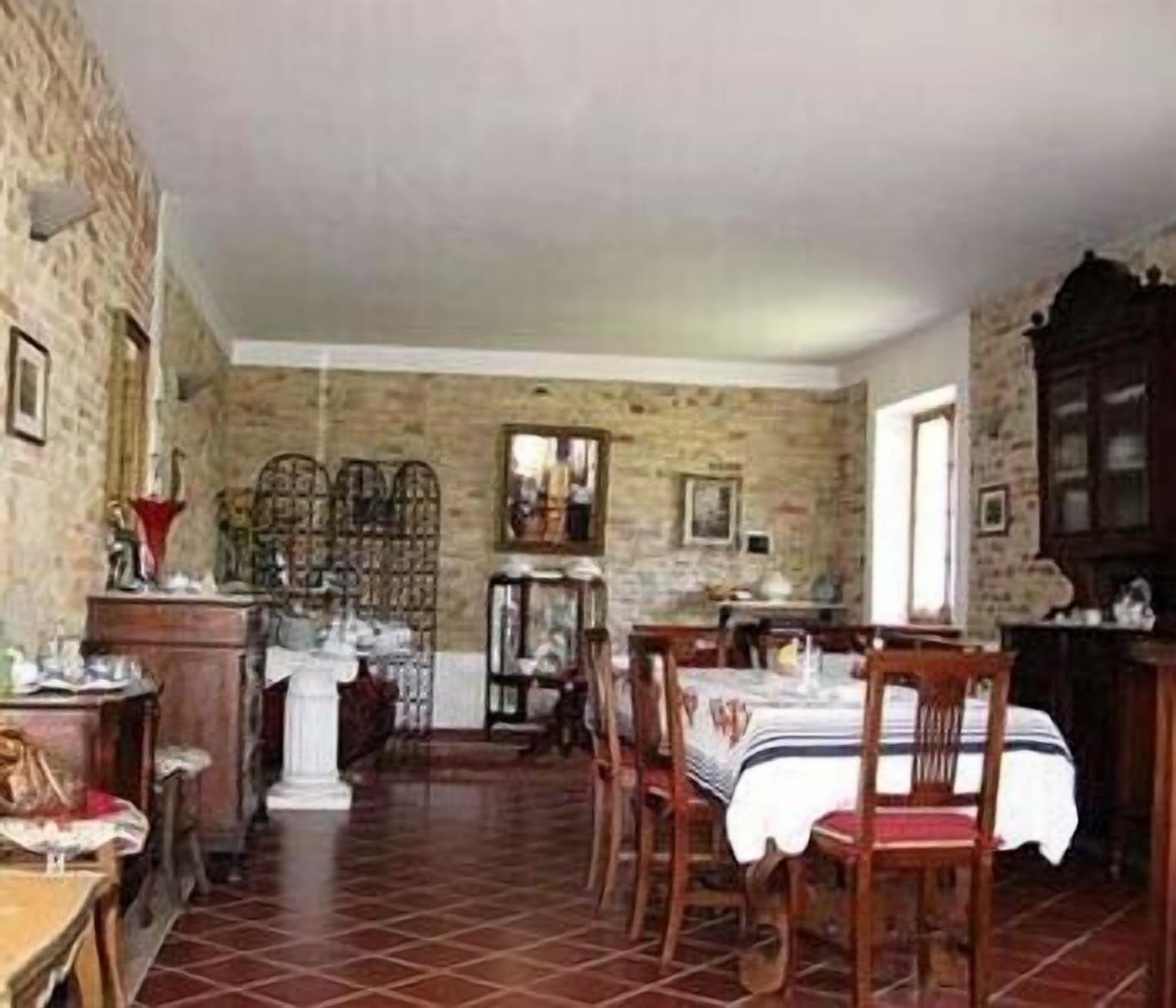 A dining area with a brick wall, a wooden table with a white tablecloth, and several chairs.