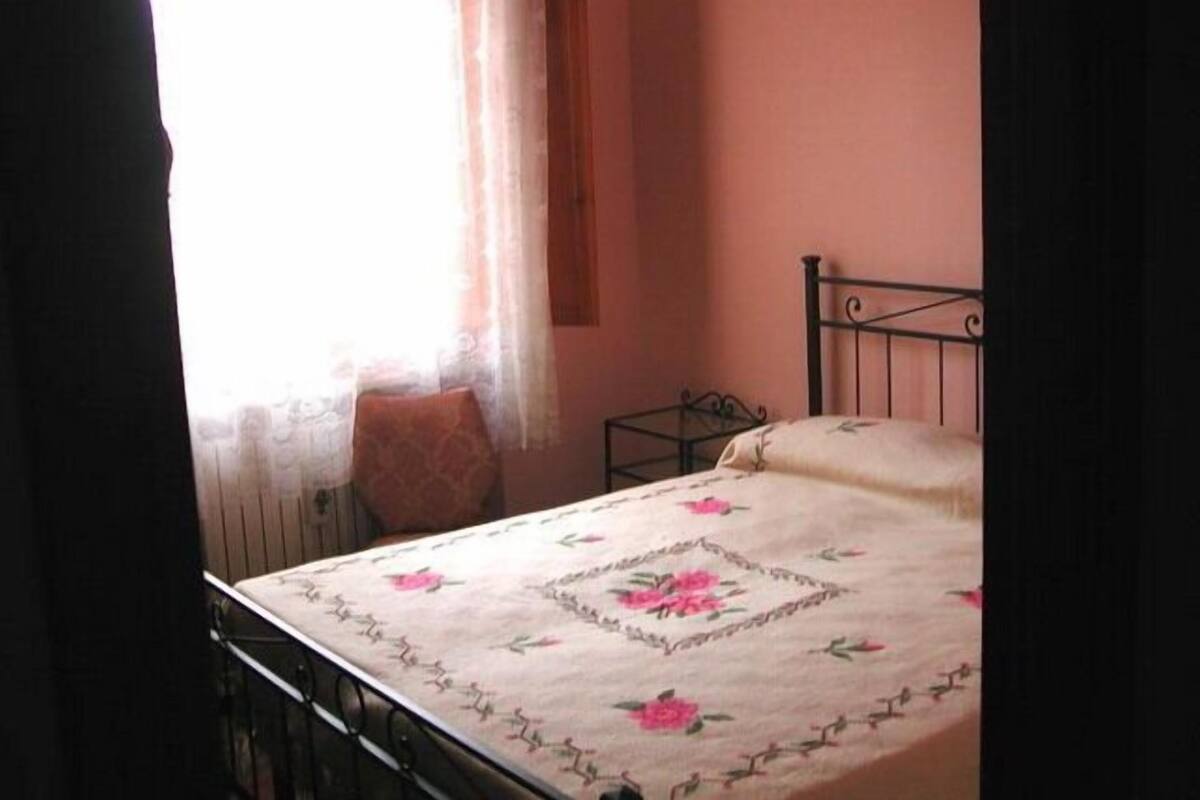 A bedroom with a bed, a chair, and a small table.