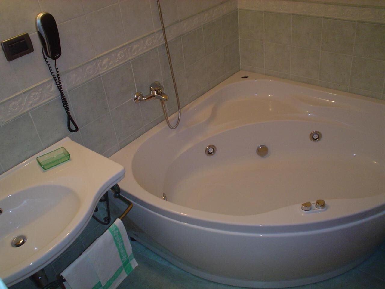 A bathroom with a bathtub, a sink, and a telephone.