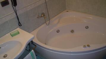 A bathroom with a bathtub, a sink, and a telephone.
