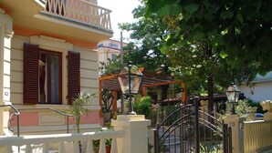 A residential building with a gated entrance, a balcony, and a garden area with potted plants. - Petit Château (Montecatini Terme)