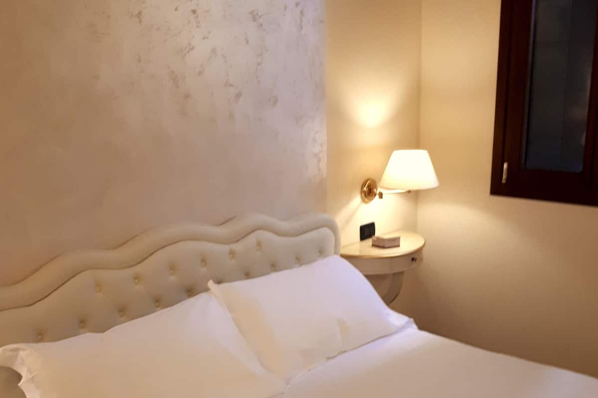 A neatly made bed with white linens in a hotel room.