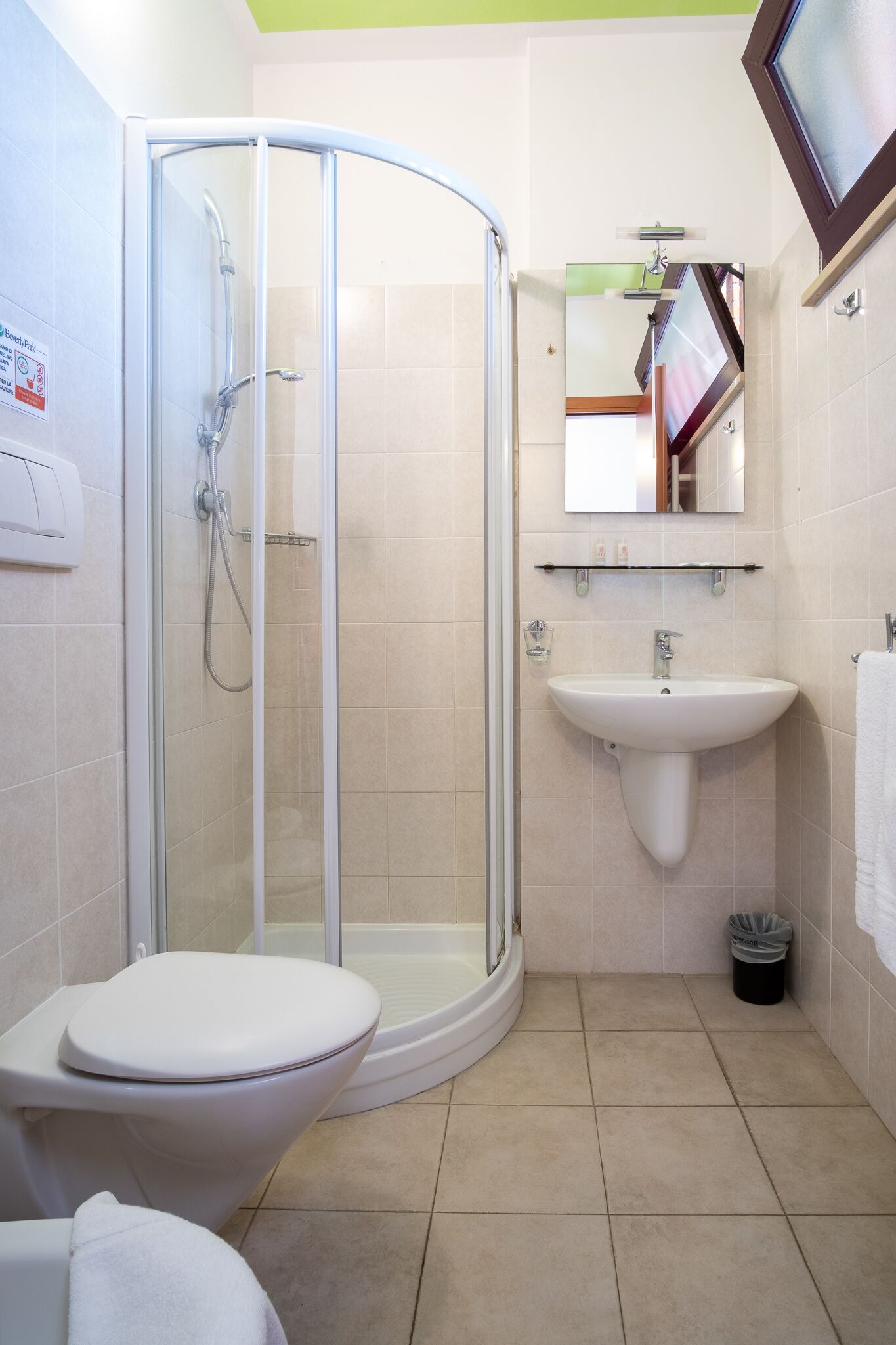 A bathroom with a glass-enclosed shower, a white sink, and a toilet.