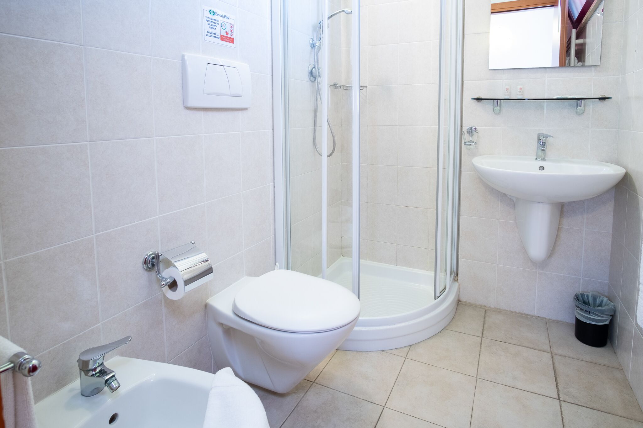 Un baño con inodoro, lavamanos y cabina de ducha de vidrio.