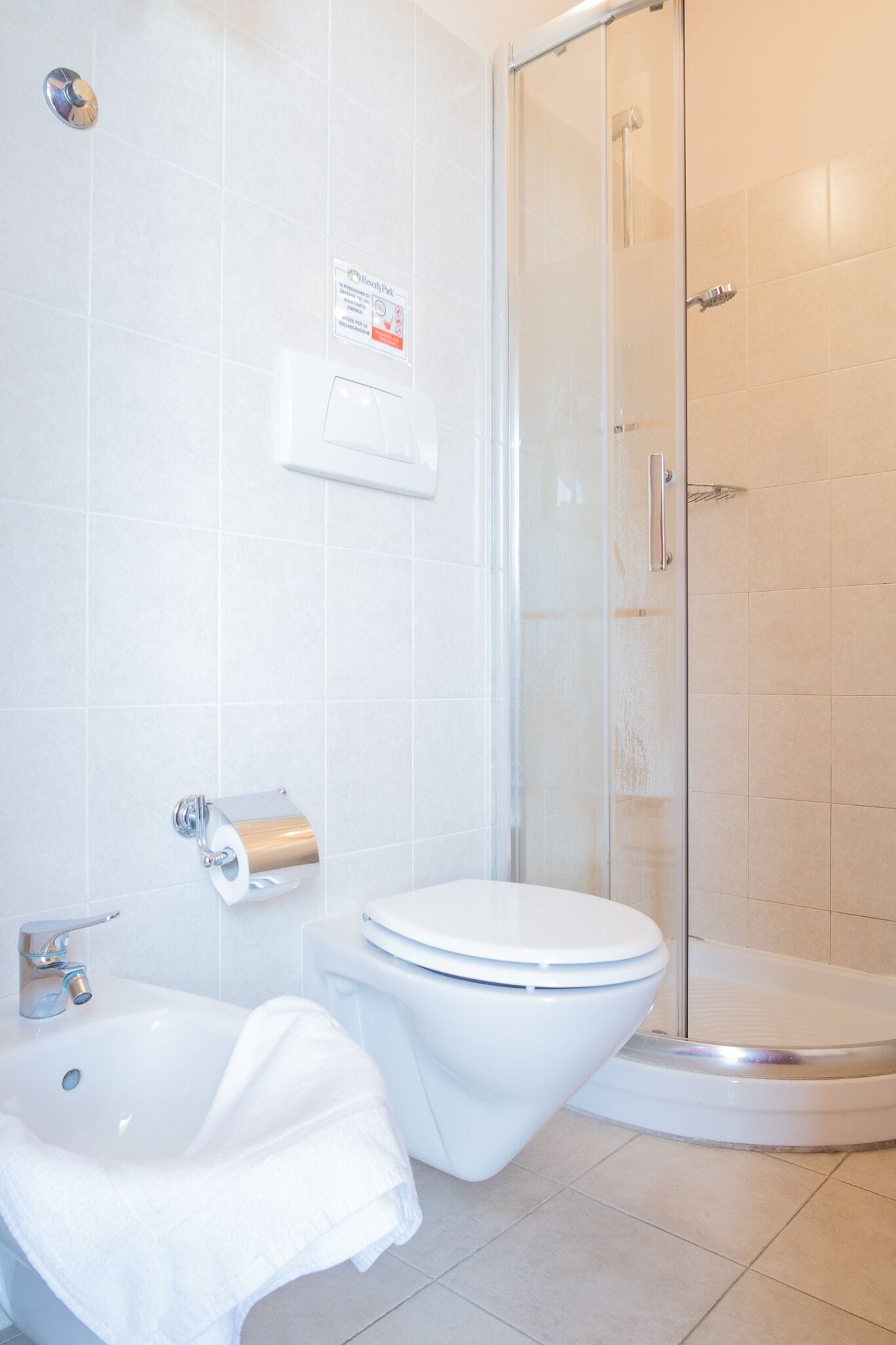 A modern bathroom with a glass-enclosed shower, a white toilet, and a sink with a towel.
