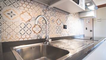 A modern kitchen with a stainless steel sink, patterned backsplash, and built-in oven.