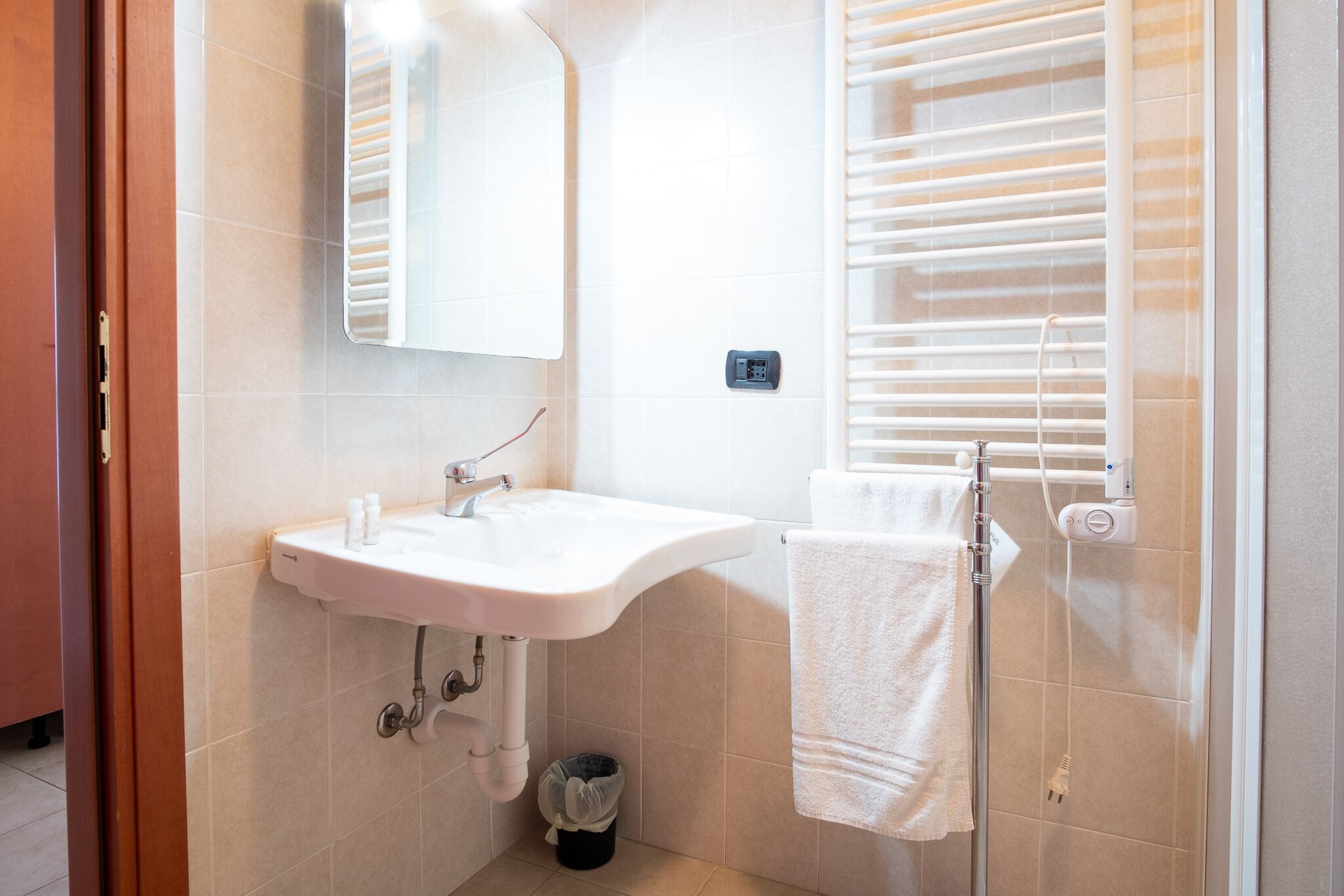 A bathroom with a sink, mirror, towel rack, and window with blinds.