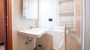 A bathroom with a sink, mirror, towel rack, and window with blinds.