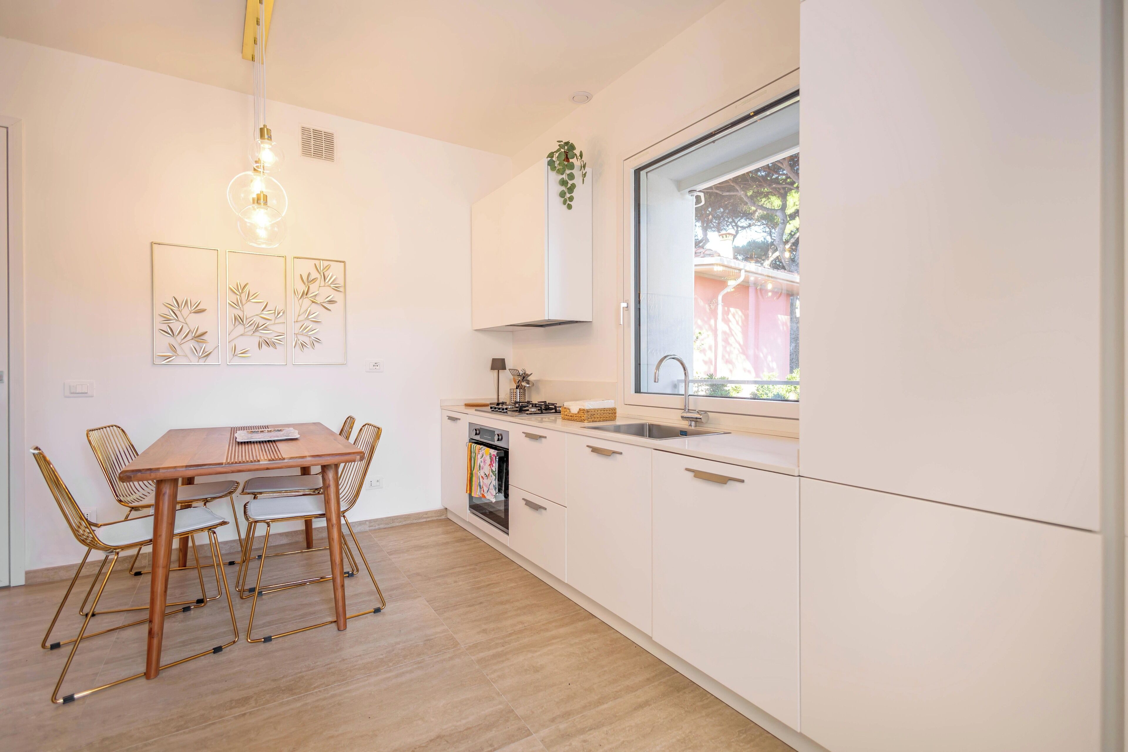 A modern kitchen with a dining table, chairs, a window, and a built-in oven.