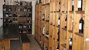 A wine cellar with wooden shelves filled with wine bottles. - Shine (Acqualagna)