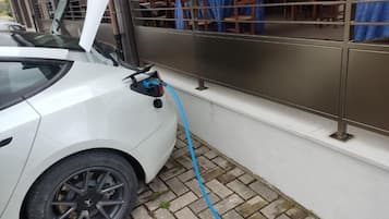 Un'auto bianca parcheggiata accanto a un edificio con un tubo blu collegato.