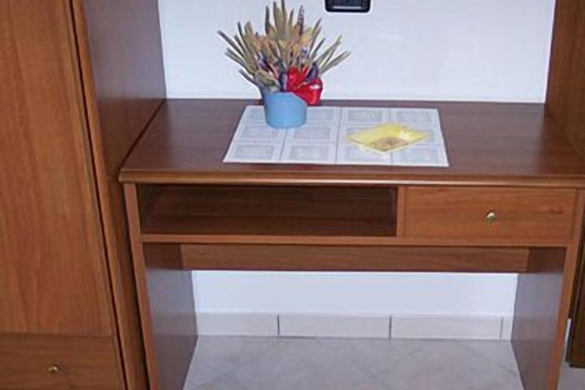 A wooden desk with a blue vase and a yellow object on top.