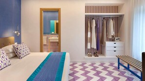 Une chambre d’hôtel moderne avec un grand lit, un dressing et un banc.
