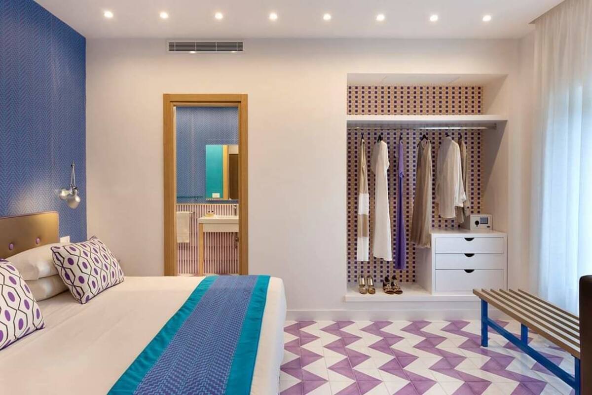 Een moderne hotelkamer met een groot bed, een inloopkast en een bank.