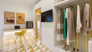 Une salle de bain moderne avec un sol à carreaux jaunes et blancs, un miroir, un lavabo et un portant à vêtements sur lequel sont disposés différents articles.