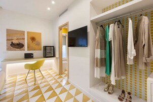 Un bagno moderno con pavimento a scacchi giallo e bianco, uno specchio, un lavandino e un appendiabiti con diversi capi di abbigliamento.