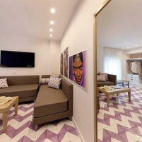 Un soggiorno moderno con un divano, un tavolino da caffè e una TV a schermo piatto montata a parete.