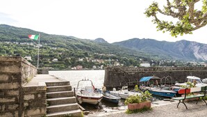 A harbor with boats docked, a flag, and a mountainous backdrop. - Hotel Belvedere (Stresa)