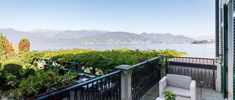 A balcony with wicker furniture, a view of a lake, and distant mountains.