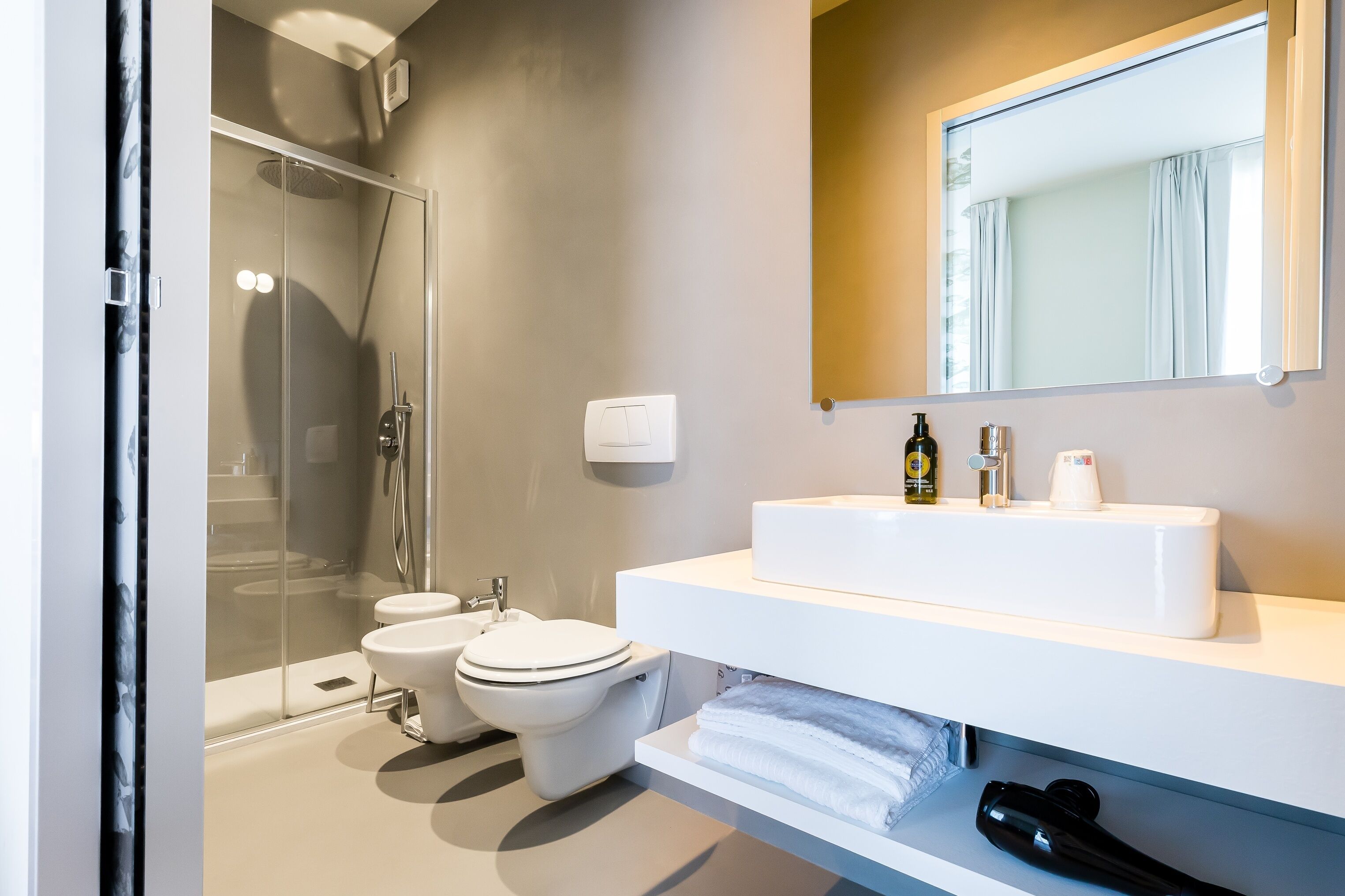 A modern bathroom with a glass-enclosed shower, a white sink, and a mirror above it.